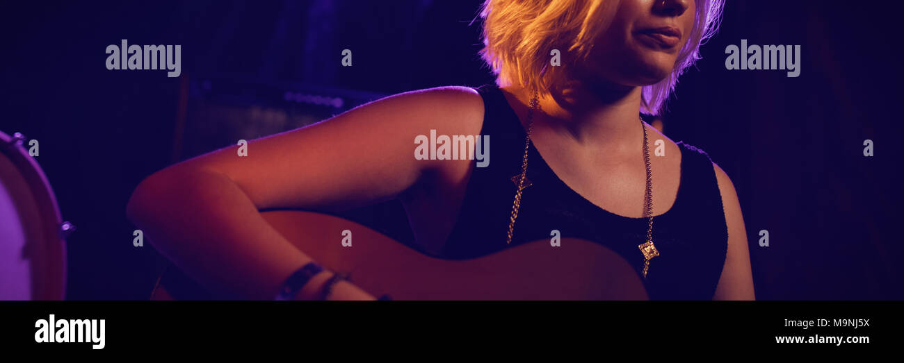 Fiducioso femmina di suonare la chitarra in discoteca Foto Stock