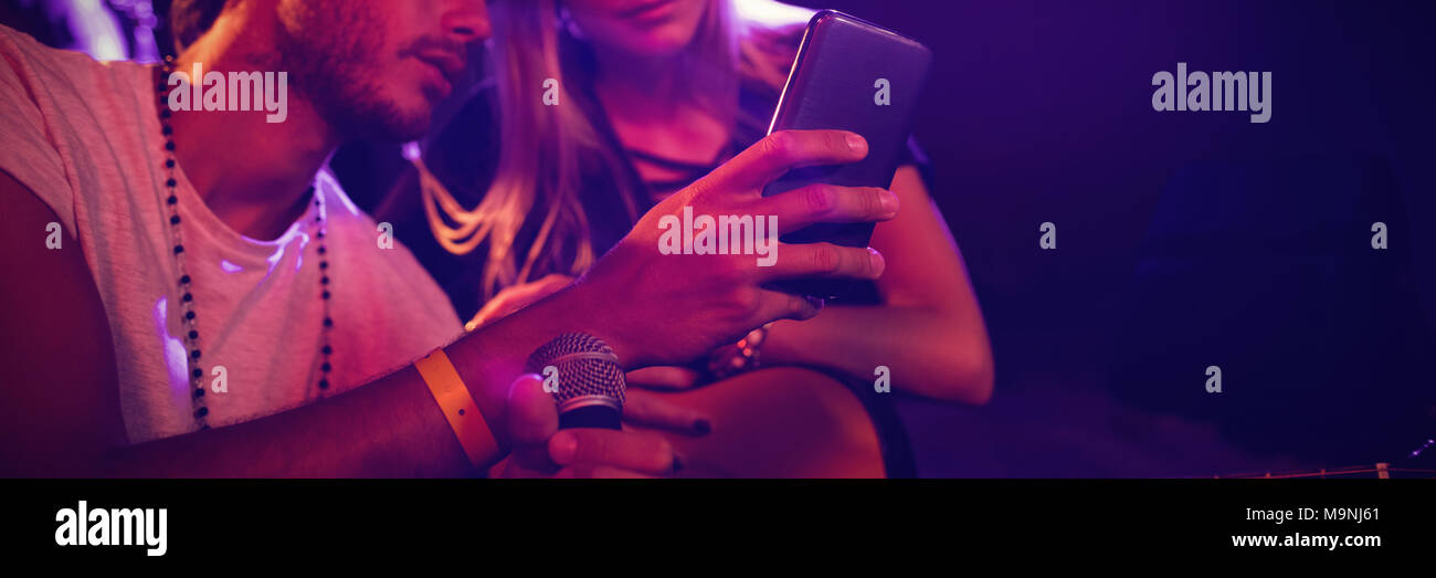 Musicisti che usano il telefono cellulare mentre si pratica in discoteca Foto Stock