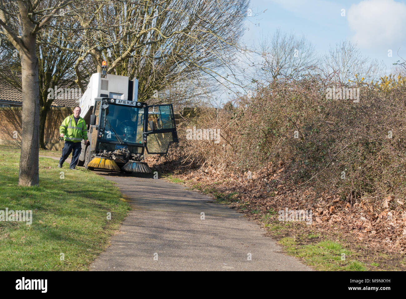 Un consiglio locale spazzatrice stradale e pavimentazione spazzatrice veicolo, la pulizia di una strada suburbana in Dorset, Regno Unito Foto Stock