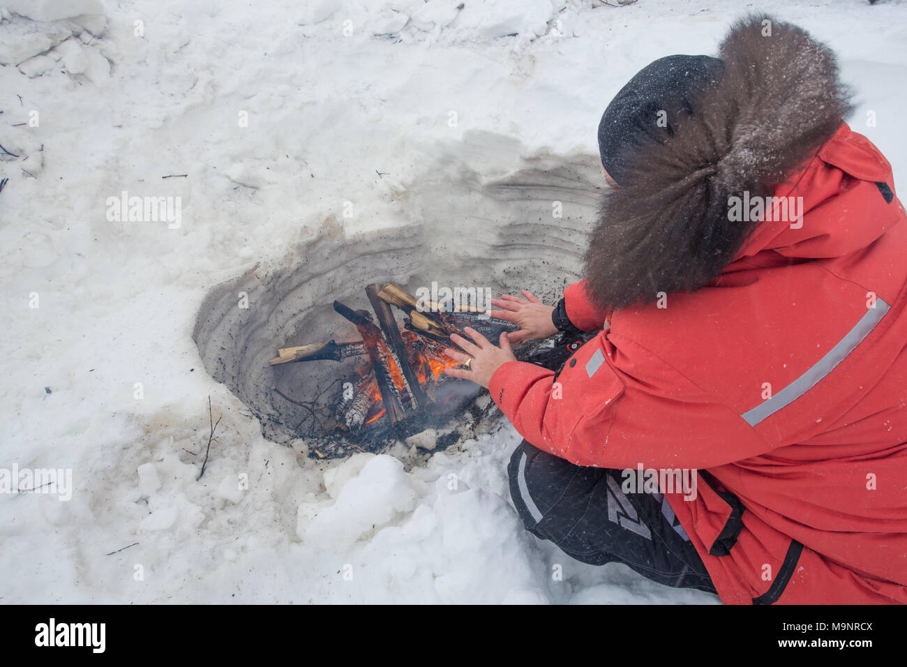 Riscaldando le mani dal fuoco nella neve Foto Stock