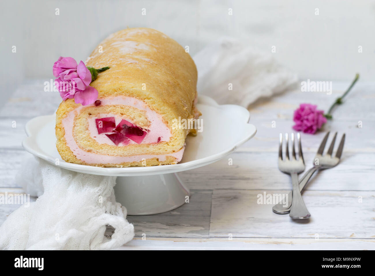 Jelly Roll torta con garofani rosa fiori su sfondo bianco Foto Stock