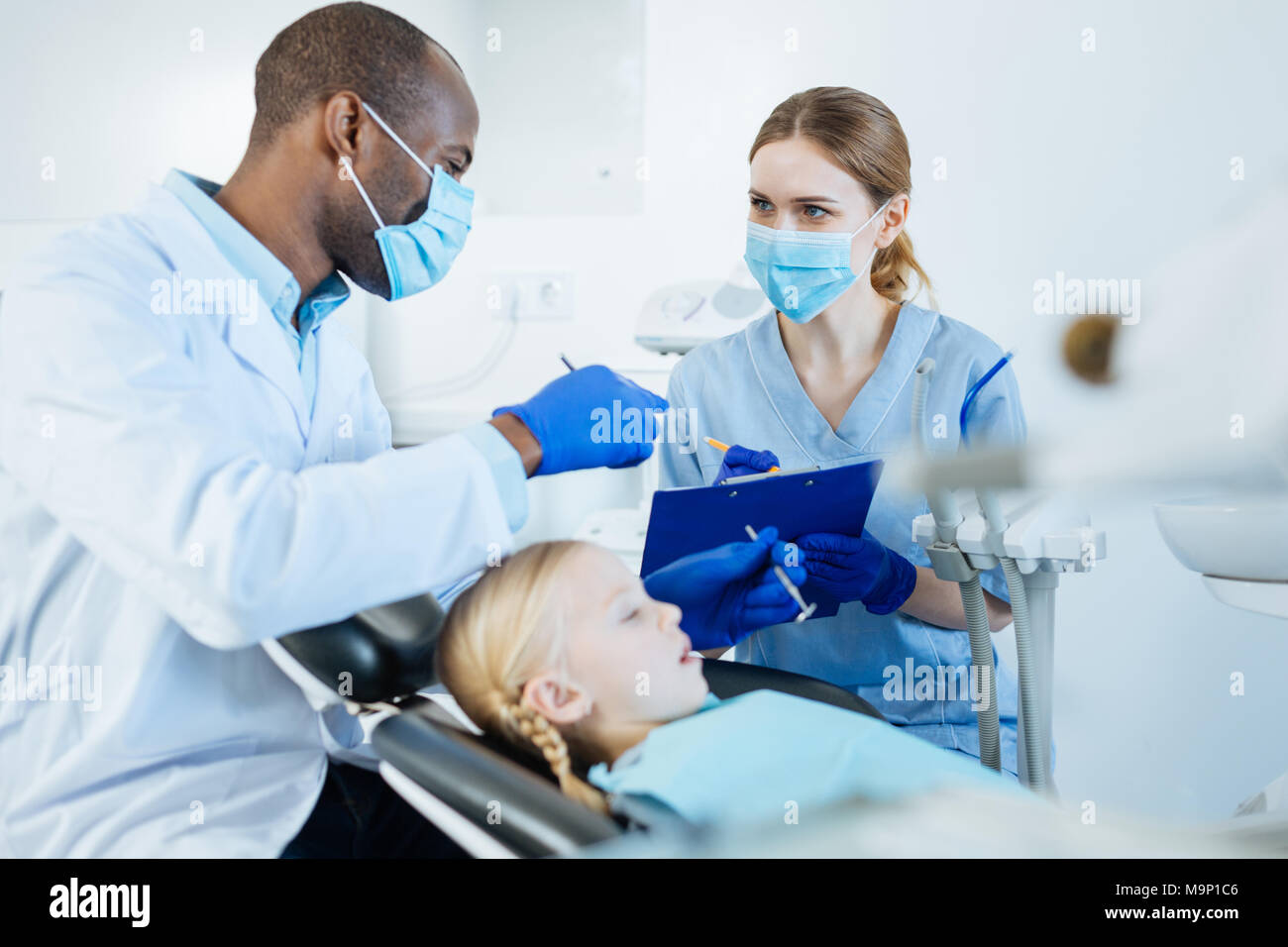 Allegro dentista a dettare le sue osservazioni per l'infermiere Foto Stock