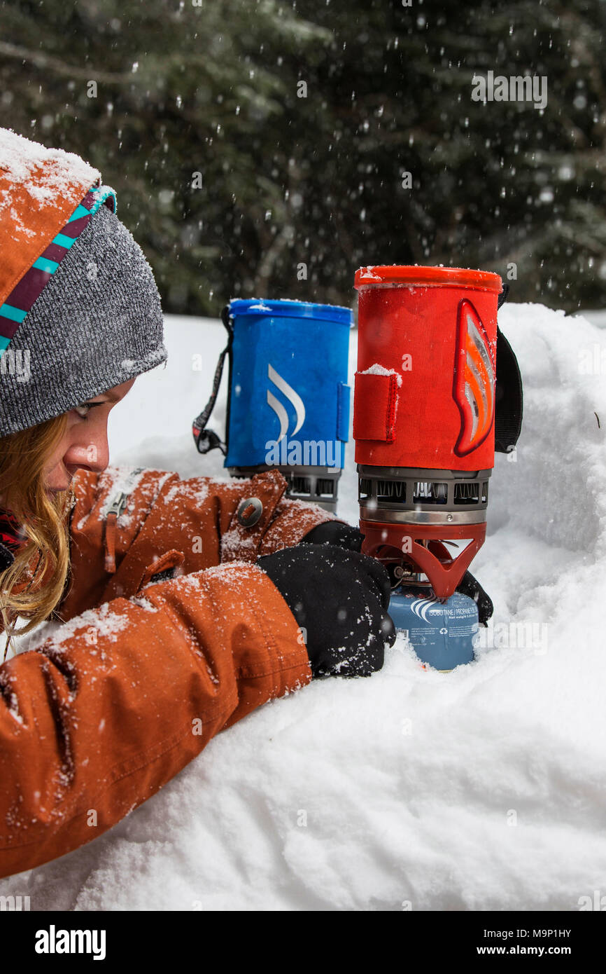 La donna a partire campstove per fare un caffè sul fornello da campeggio in inverno, Sureanu, Romania Foto Stock
