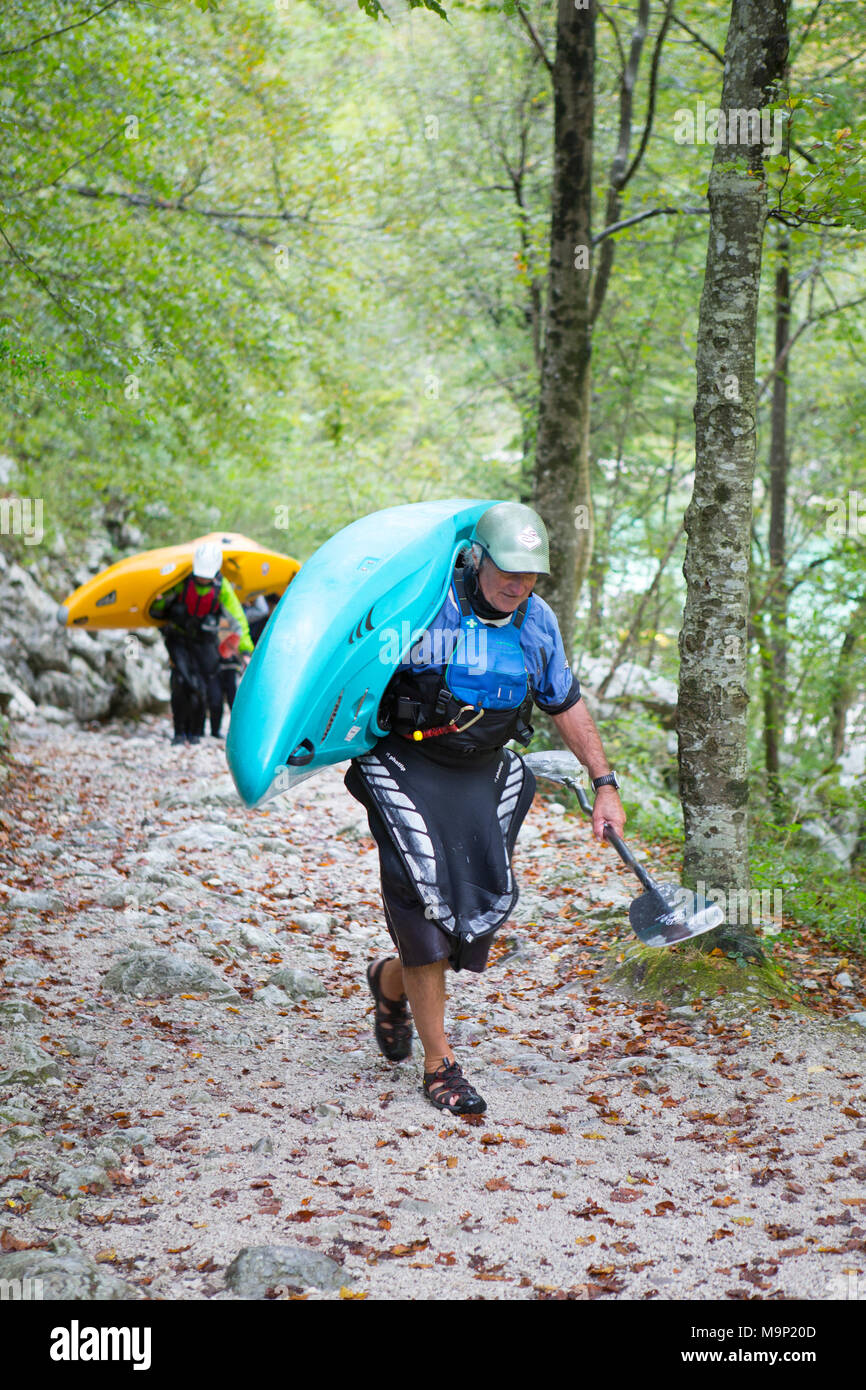 Kayakers che trasportano i loro variopinti kayak sul fiume Soca vicino a Bovec, Triglav, Slovenia Foto Stock
