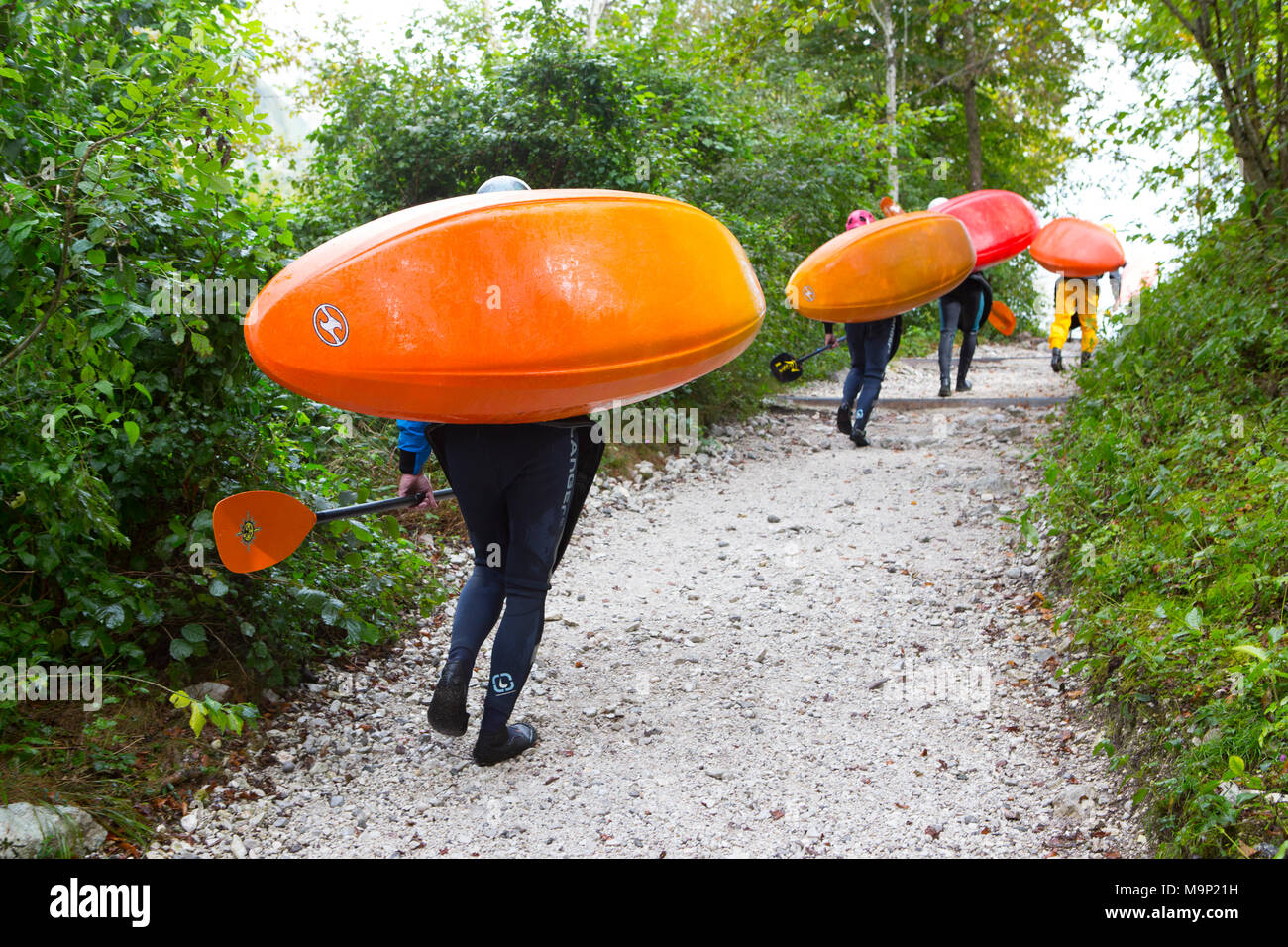 Kayakers che trasportano i loro variopinti kayak sul fiume Soca vicino a Bovec, Triglav, Slovenia Foto Stock