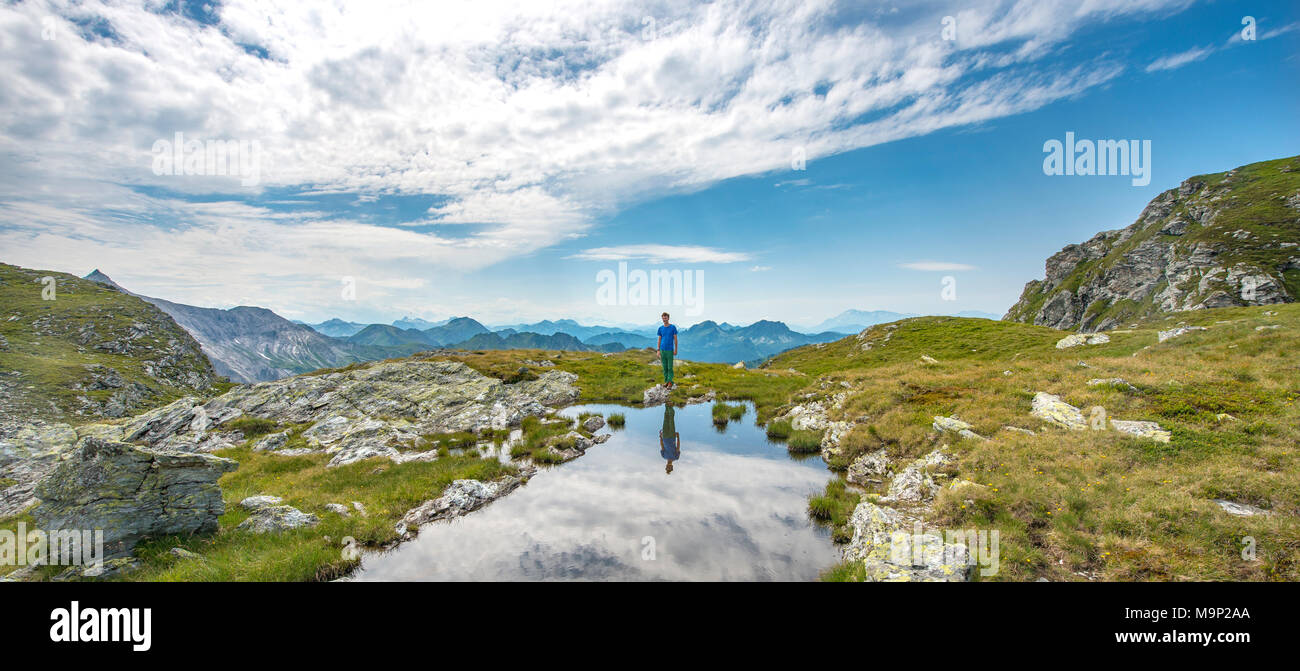 Escursionista si riflette in un piccolo lago, Schladminger Höhenweg, Schladminger Tauern, Schladming, Stiria, Austria Foto Stock