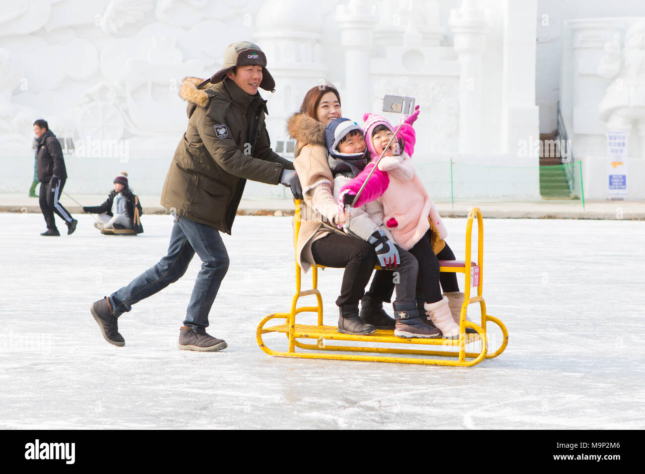 Un asiatico cerca famiglia è divertirsi facendo un selfie su una slitta di gruppo presso il fiume congelato al Hwacheon Sancheoneo Festival di ghiaccio. Il Hwacheon Sancheoneo Festival di ghiaccio è una tradizione per il popolo coreano. Ogni anno nel mese di gennaio la folla si riuniranno presso il fiume congelato per celebrare il freddo e la neve dell'inverno. Attrazione principale è la pesca sul ghiaccio. Giovani e vecchi attendere pazientemente su un piccolo buco nel ghiaccio per una trota di mordere. In tende che possono ottenere il pesce grigliato dopo che loro sono mangiati. Tra le altre attività sono corse in slittino e pattinaggio sul ghiaccio. La vicina regione Pyeongchang ospiterà le Olimpiadi Invernali nel Foto Stock