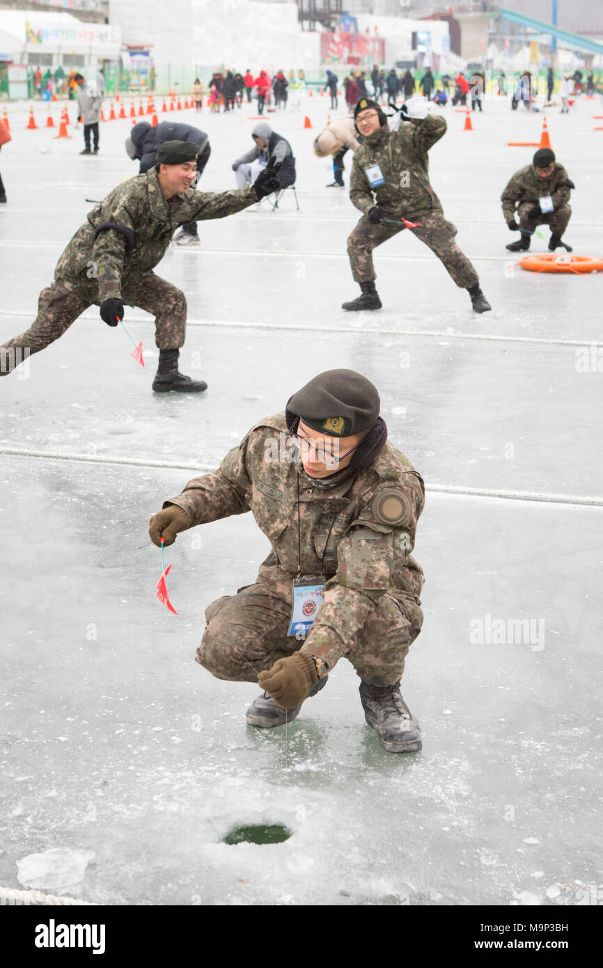Corea del Sud i soldati dell esercito sono scherzando durante la pesca sul ghiaccio festival presso Hwacheon Sancheoneo nella regione del Gangwon-do di Corea del Sud. Il Hwacheon Sancheoneo Festival di ghiaccio è una tradizione per il popolo coreano. Ogni anno nel mese di gennaio la folla si riuniranno presso il fiume congelato per celebrare il freddo e la neve dell'inverno. Attrazione principale è la pesca sul ghiaccio. Giovani e vecchi attendere pazientemente su un piccolo buco nel ghiaccio per una trota di mordere. In tende possono lasciare il pesce grigliato dopo che loro sono mangiati. Tra le altre attività sono corse in slittino e pattinaggio sul ghiaccio. La vicina regione Pyeongchang ospiterà le Olimpiadi Invernali nel Foto Stock