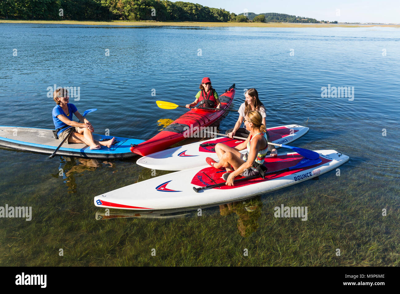 Le donne in piedi up paddle boarding e kayak sul fiume Essex a Cox Prenotazione in Essex, Massachusetts Foto Stock