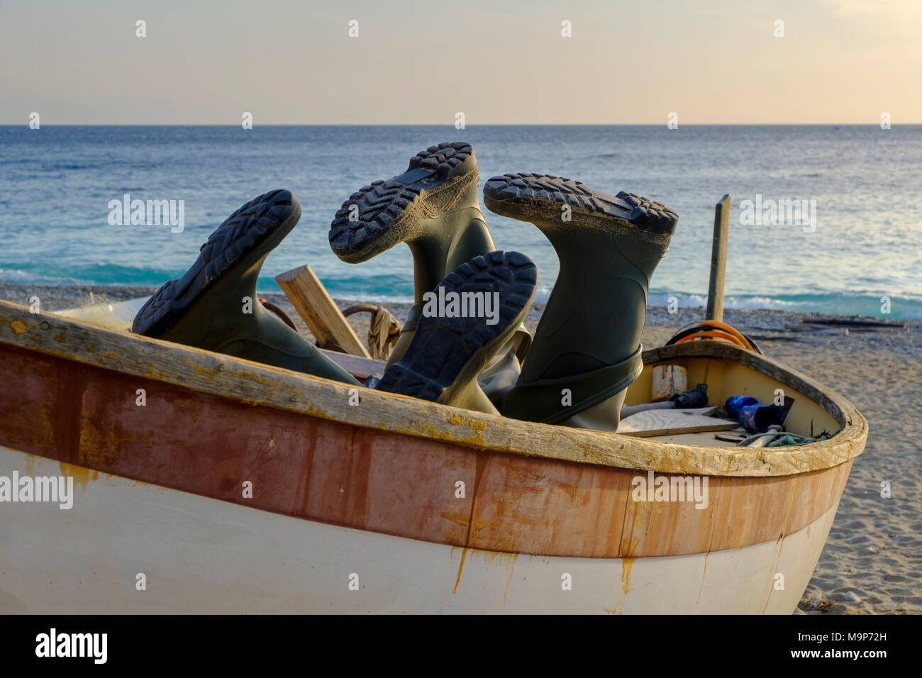 Stivali di gomma in una barca da pesca sulla spiaggia, Noli, la Riviera di Ponente, Liguria, Italia Foto Stock