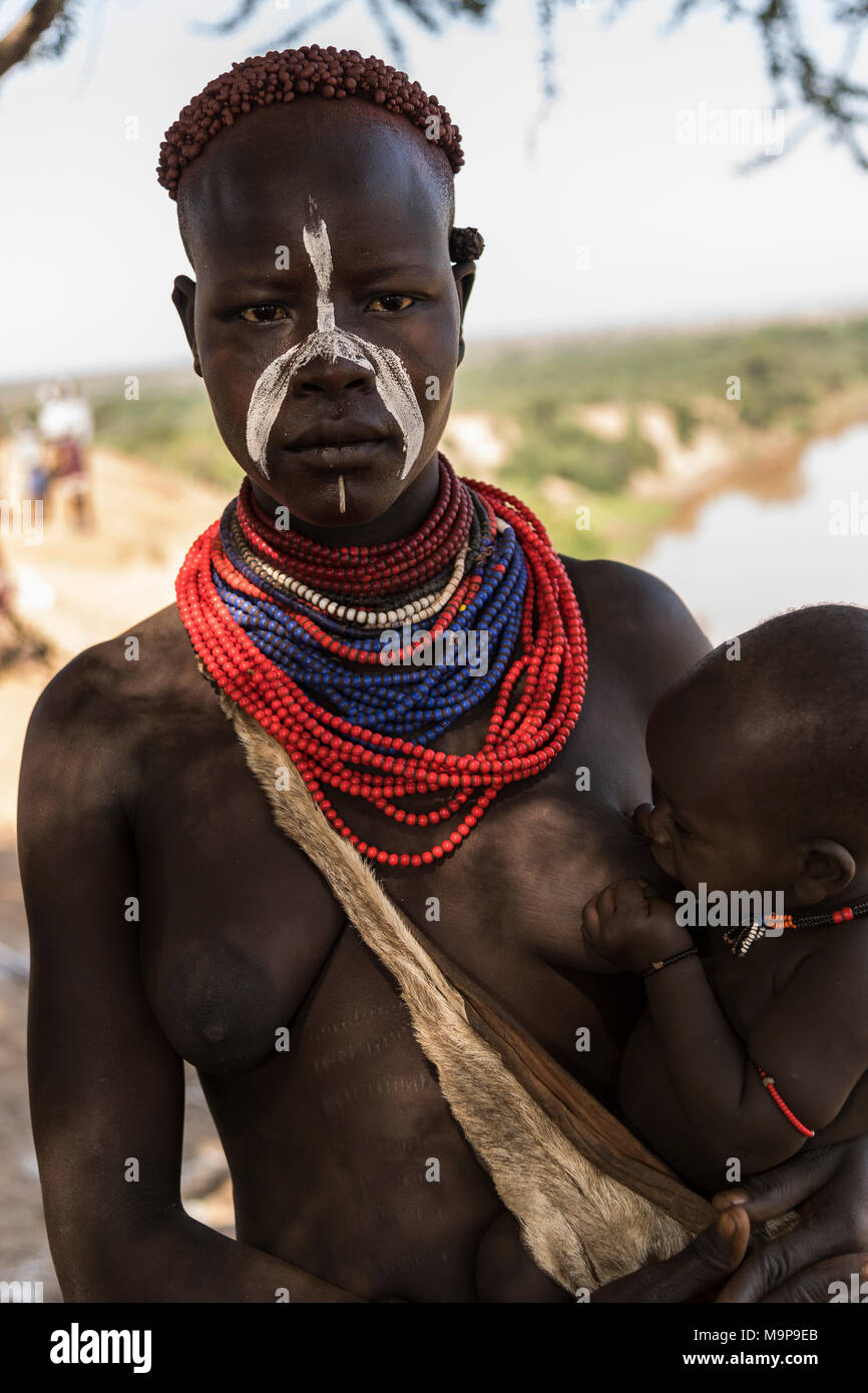 Giovane donna allattamento baby, Karo tribù, Omo, sud della nazionalità delle nazioni e dei popoli " Regione, Etiopia Foto Stock