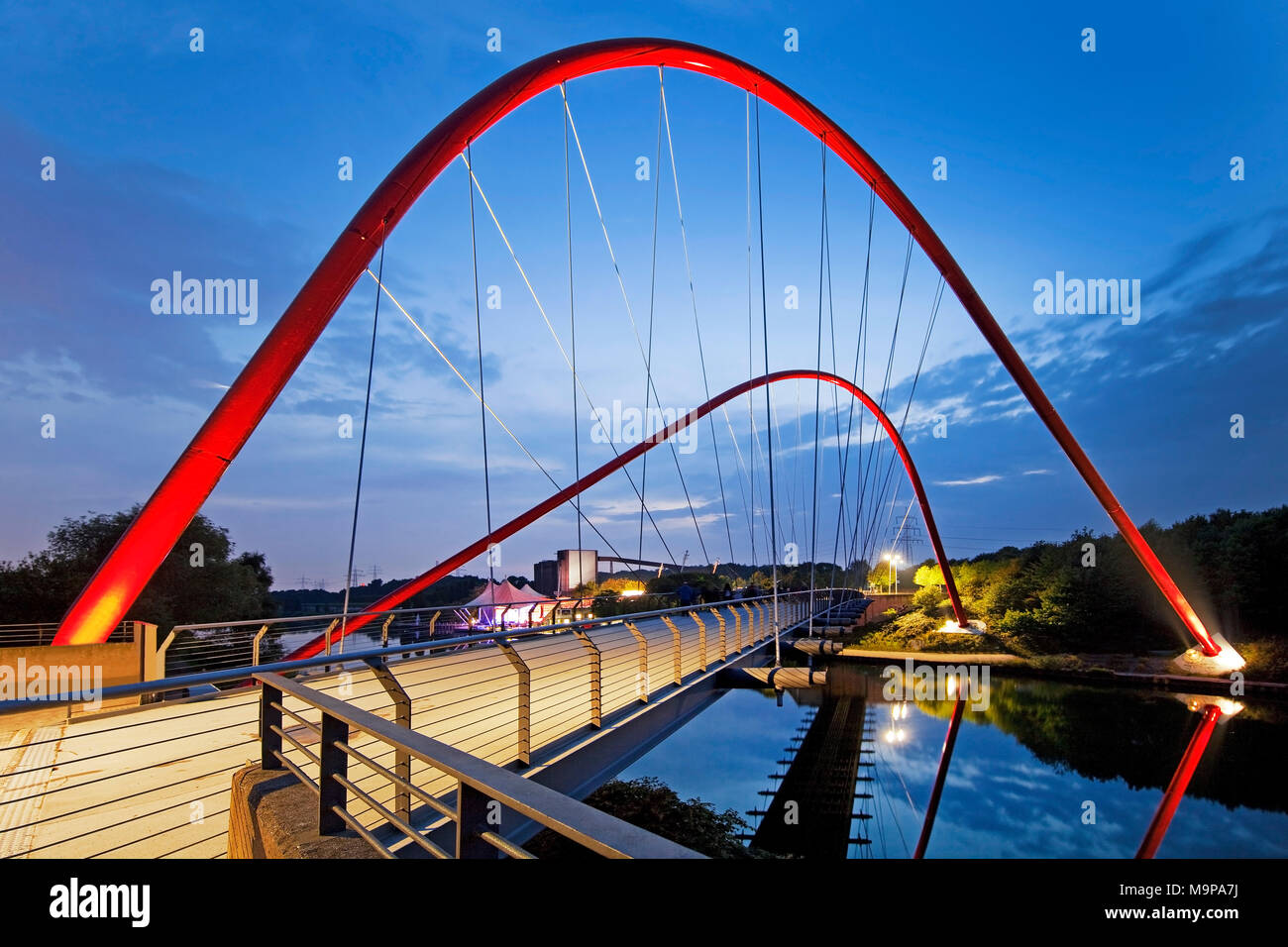 Moderno rosso in acciaio ponte ad arco sopra la Rhine-Herne-Canal, crepuscolo, Nordsternpark, Gelsenkirchen, zona della Ruhr Foto Stock