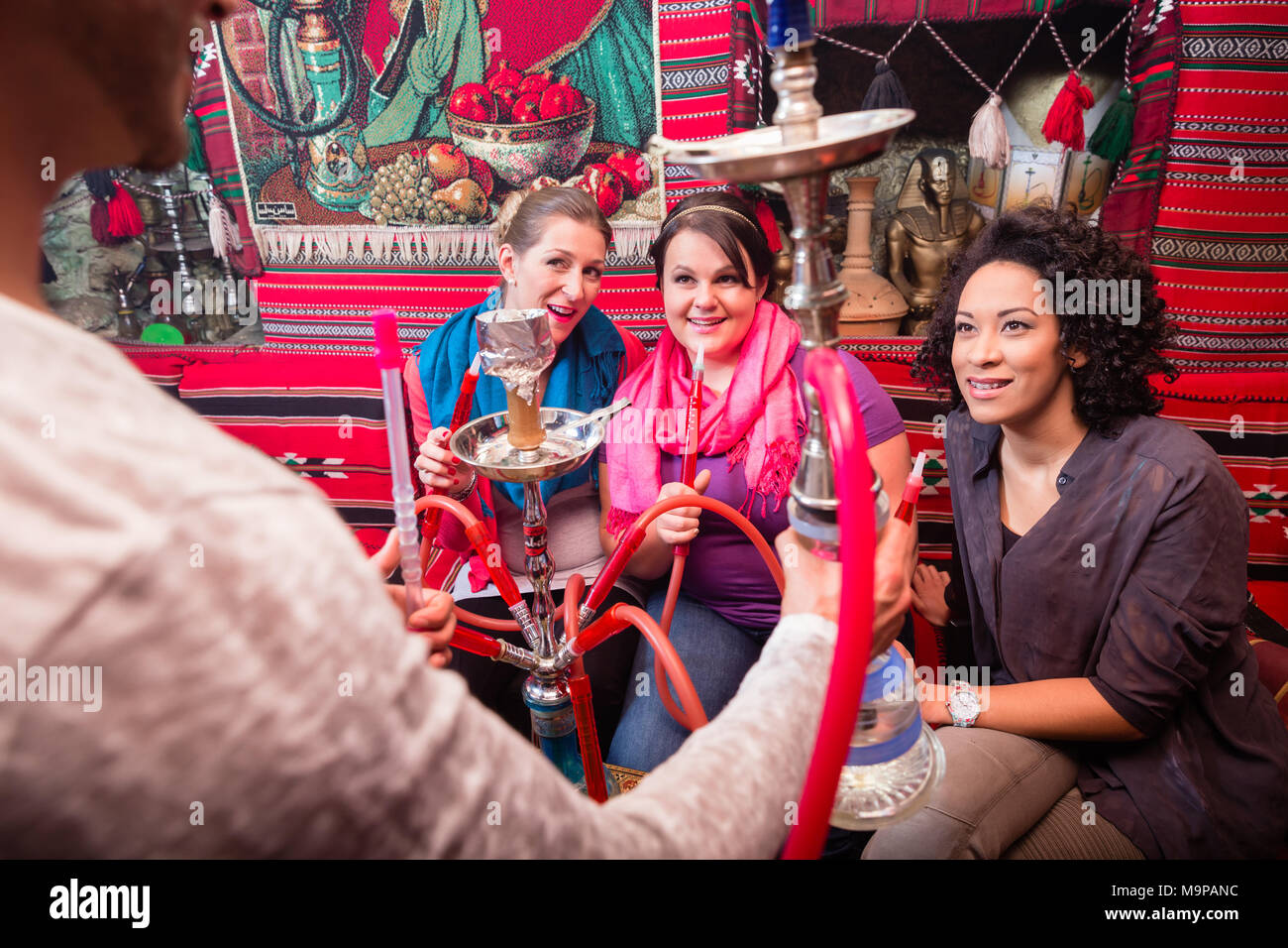 Gruppo su donne e uomini di essere servito un narghilè in shisha cafe Foto Stock