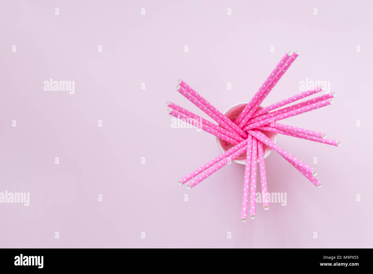 Angolo di Alta Vista del bicchiere di carta con rose paillette potabile polka design sul rosa pastello minima di sfondo concetto creativo. Spazio per la copia. Foto Stock