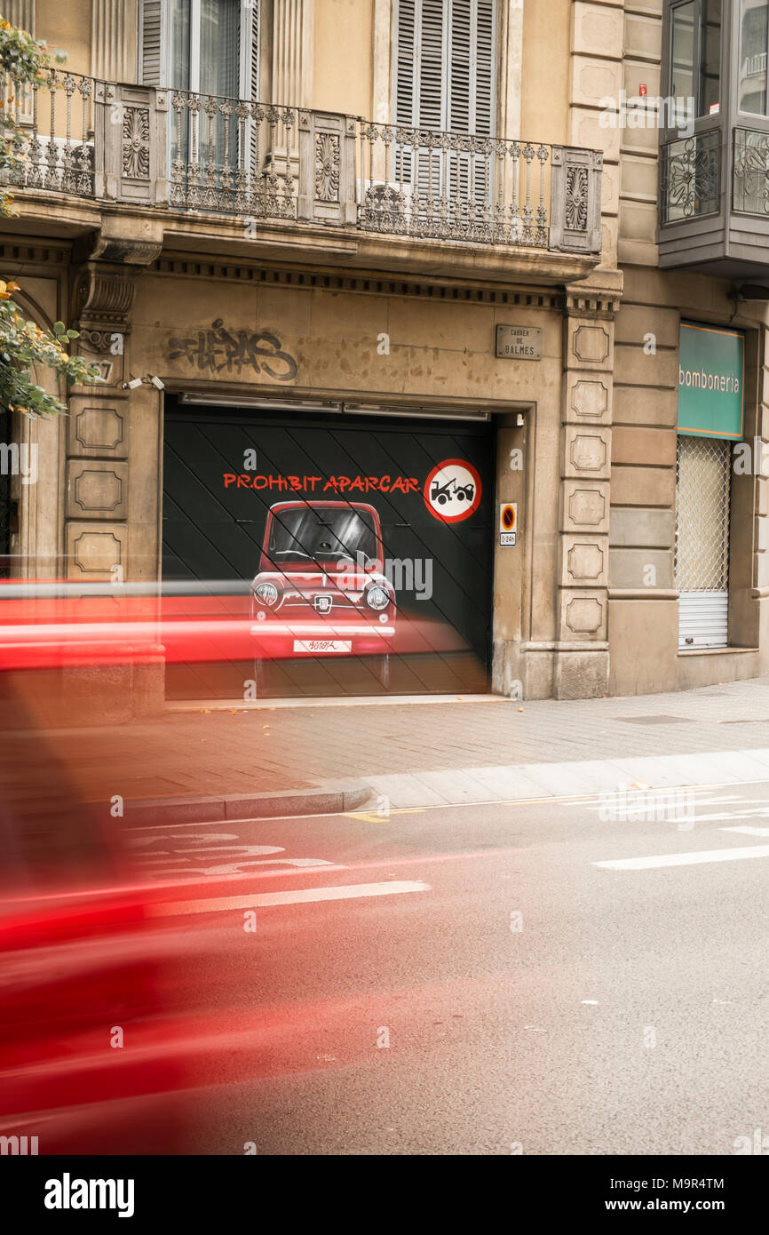 La sfocatura in movimento di una macchina velocizzando il passato un artistico "parcheggio vietato' segno dipinto su una porta di garage, a Barcellona, Spagna. Il colore rosso del tema. Foto Stock