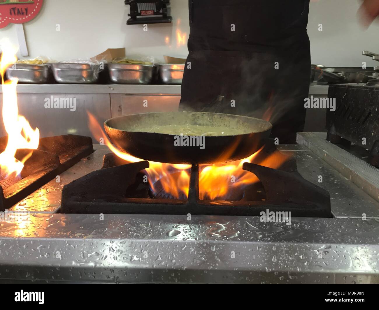 La cucina dello Chef con il fuoco in padella.professionale chef in una  cucina commerciale cucina stile flambe Foto stock - Alamy