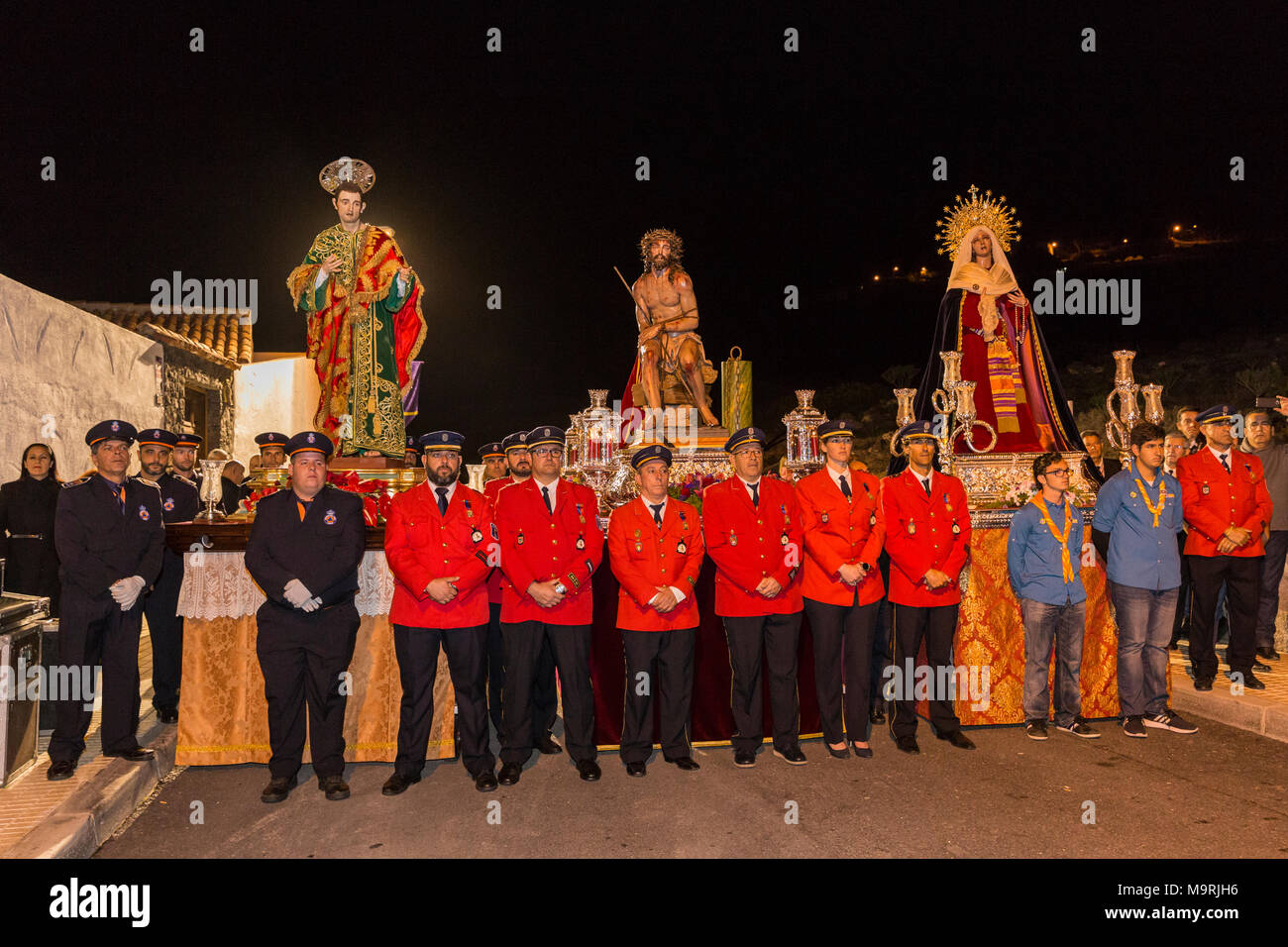 I membri del servizio incendi locale, vestito in uniforme, prendendo parte a una processione religiosa il lunedì della settimana santa, con lifesize statue di Gesù Chri Foto Stock