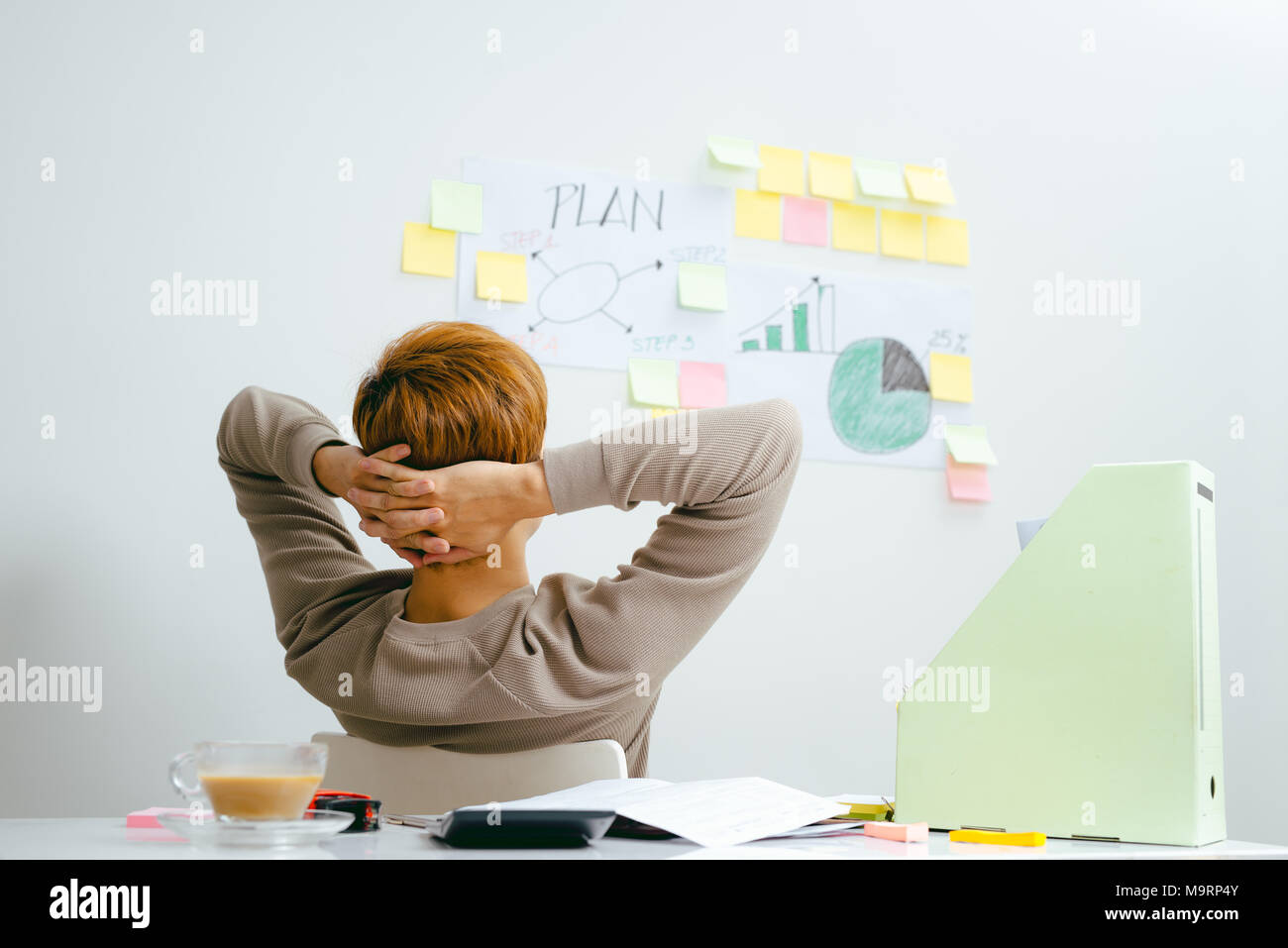 Giovane uomo asiatico seduto davanti al suo piano finanziario in camera Foto Stock