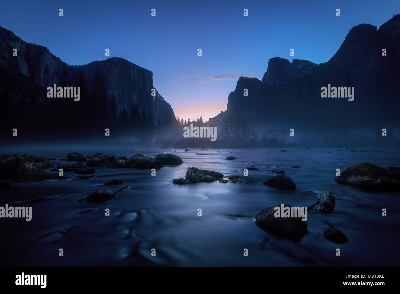 Blu nebbia alba sulle scogliere di granito e il fiume Merced nel Parco Nazionale di Yosemite Foto Stock