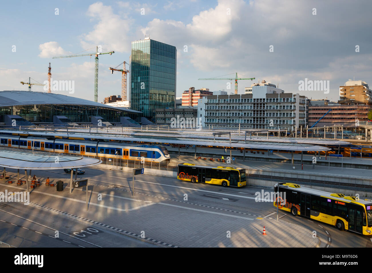 Le piattaforme di Utrecht Centraal stazione ferroviaria con treni e la stazione degli autobus con lasciando gli autobus in una giornata di sole. Utrecht, Paesi Bassi. Foto Stock