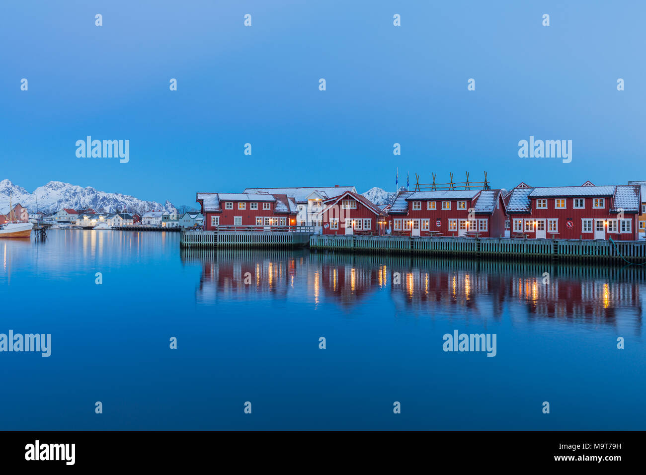 Rorbuer sono riflessi al crepuscolo in acque calme nel villaggio di pescatori Svolvaer, isole Lofoten. Foto Stock