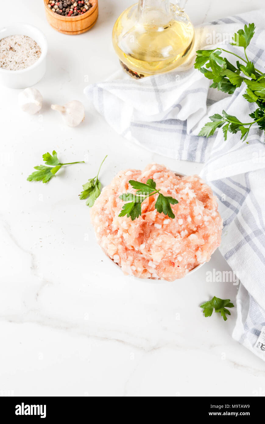 Il pollo crudo o in Turchia le carni macinate in bianco ciotola con olio, le spezie e le erbe su sfondo chiaro. Copia spazio sopra Foto Stock