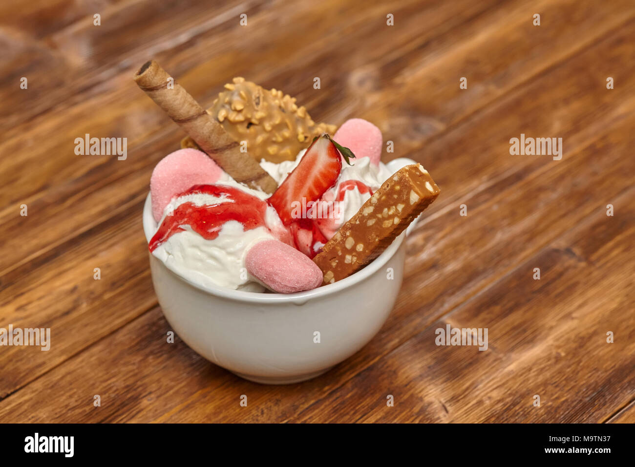 Gelato gelato cocktail nella ciotola con il wafer e candy su sfondo di legno Foto Stock