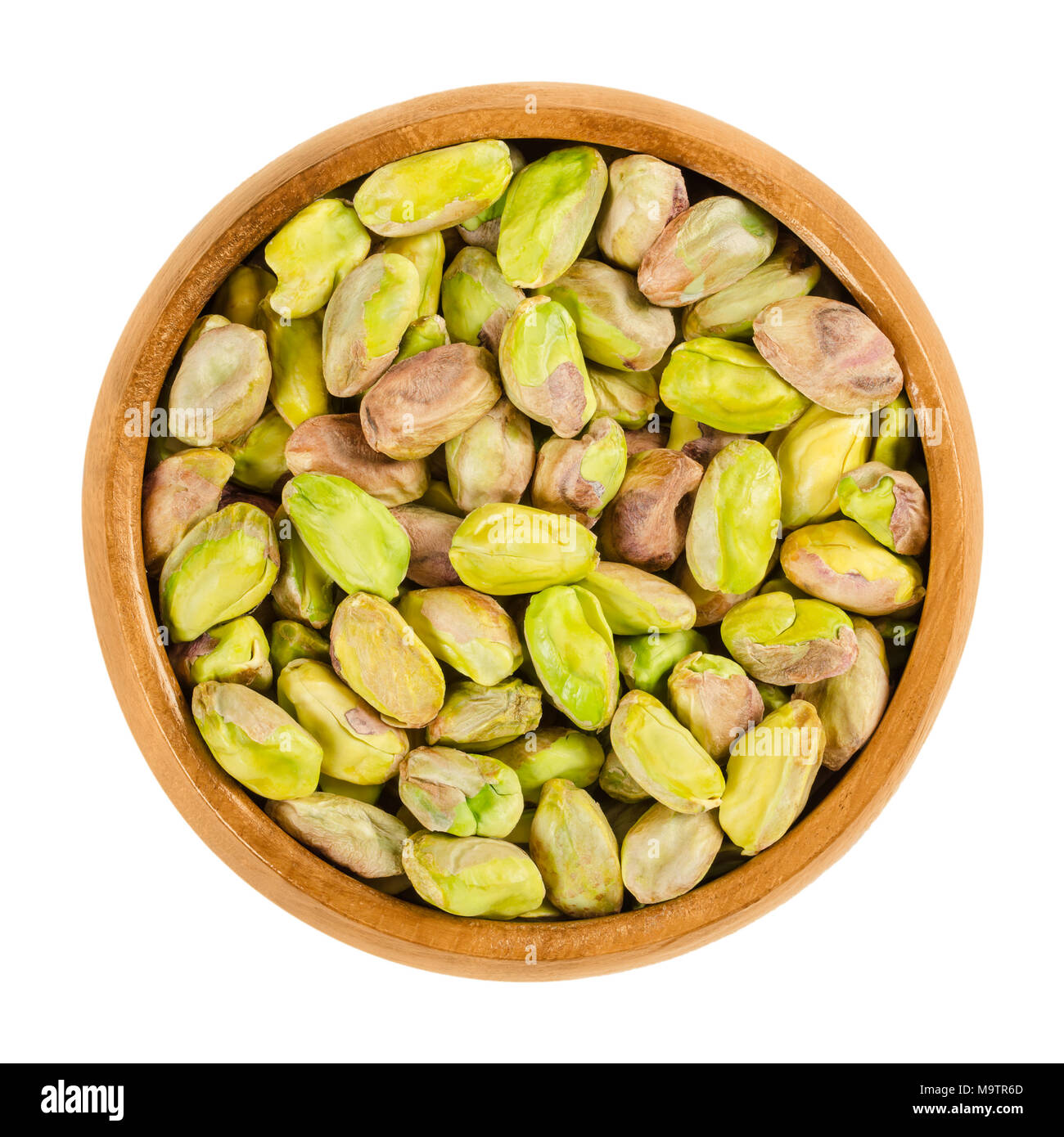 Sgusciate, pistacchi tostati in ciotola di legno. Il verde di sementi e di frutti maturi di Pistacia vera, utilizzato come snack. Isolate il cibo macro foto da vicino da sopra Foto Stock