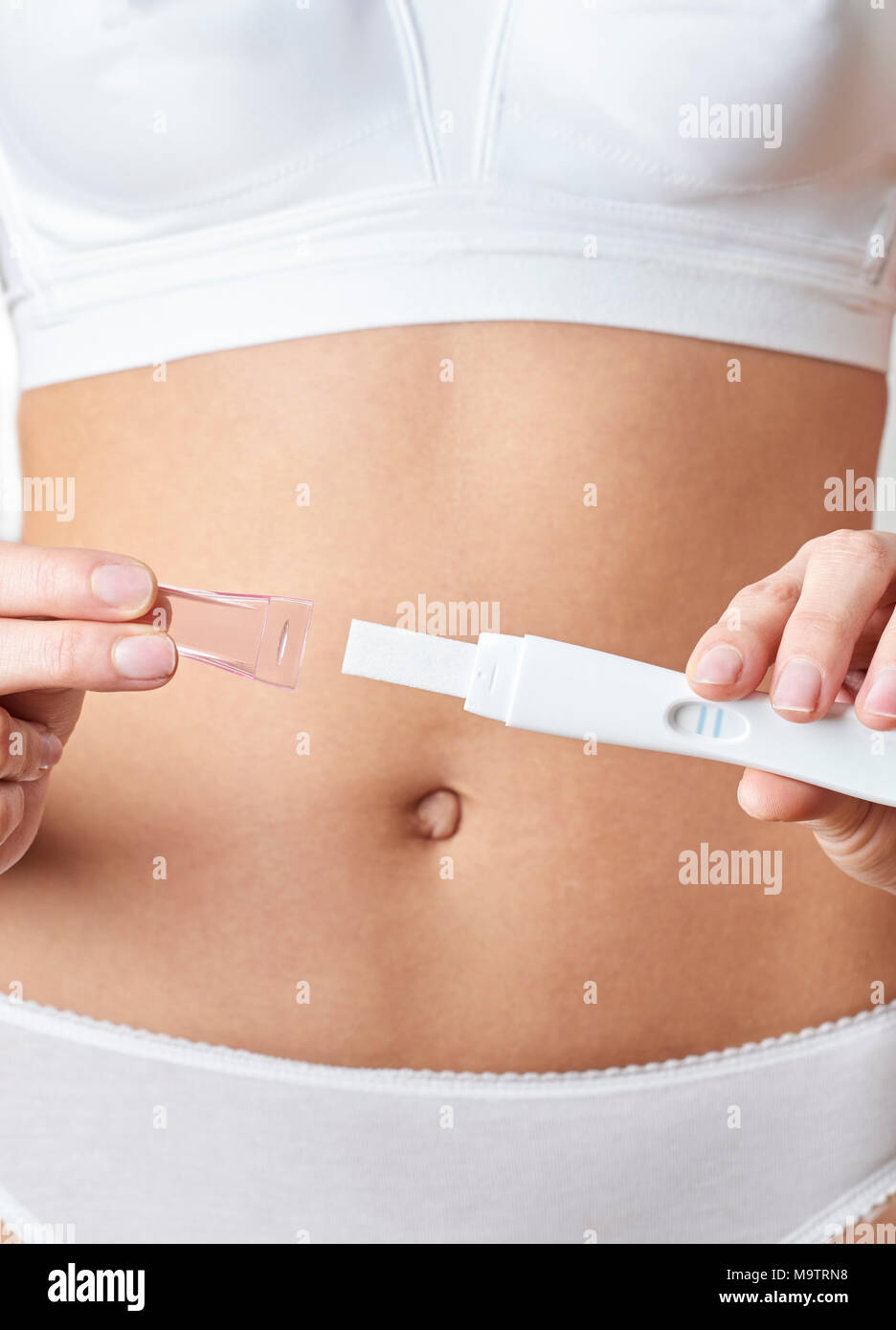 Close up della donna in biancheria intima Holding Home positivi ai test di gravidanza Foto Stock