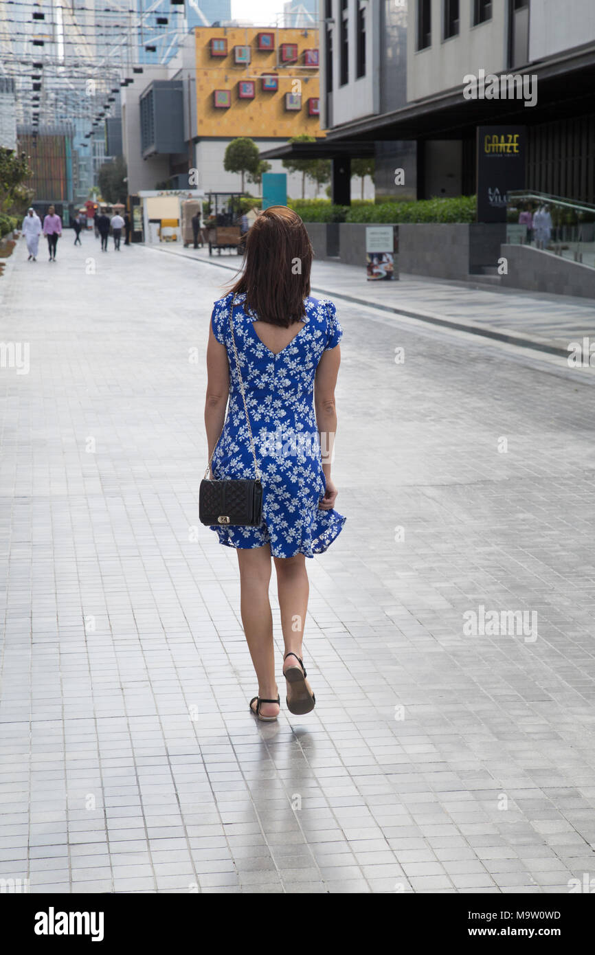 Vista posteriore di una donna che indossa blu abito floreale a piedi in strada Foto Stock