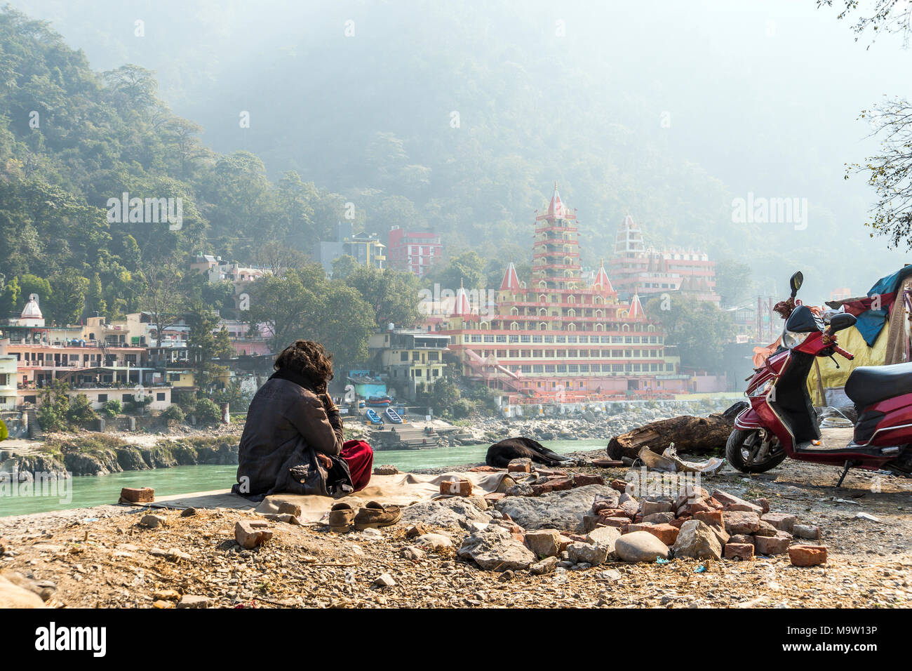 Povero uomo si siede sulle sponde del fiume Gange e guarda verso il tempio Tera Manzil Tempio. La preghiera del mattino davanti alla Santa Sede. La meditazione in Ri Foto Stock