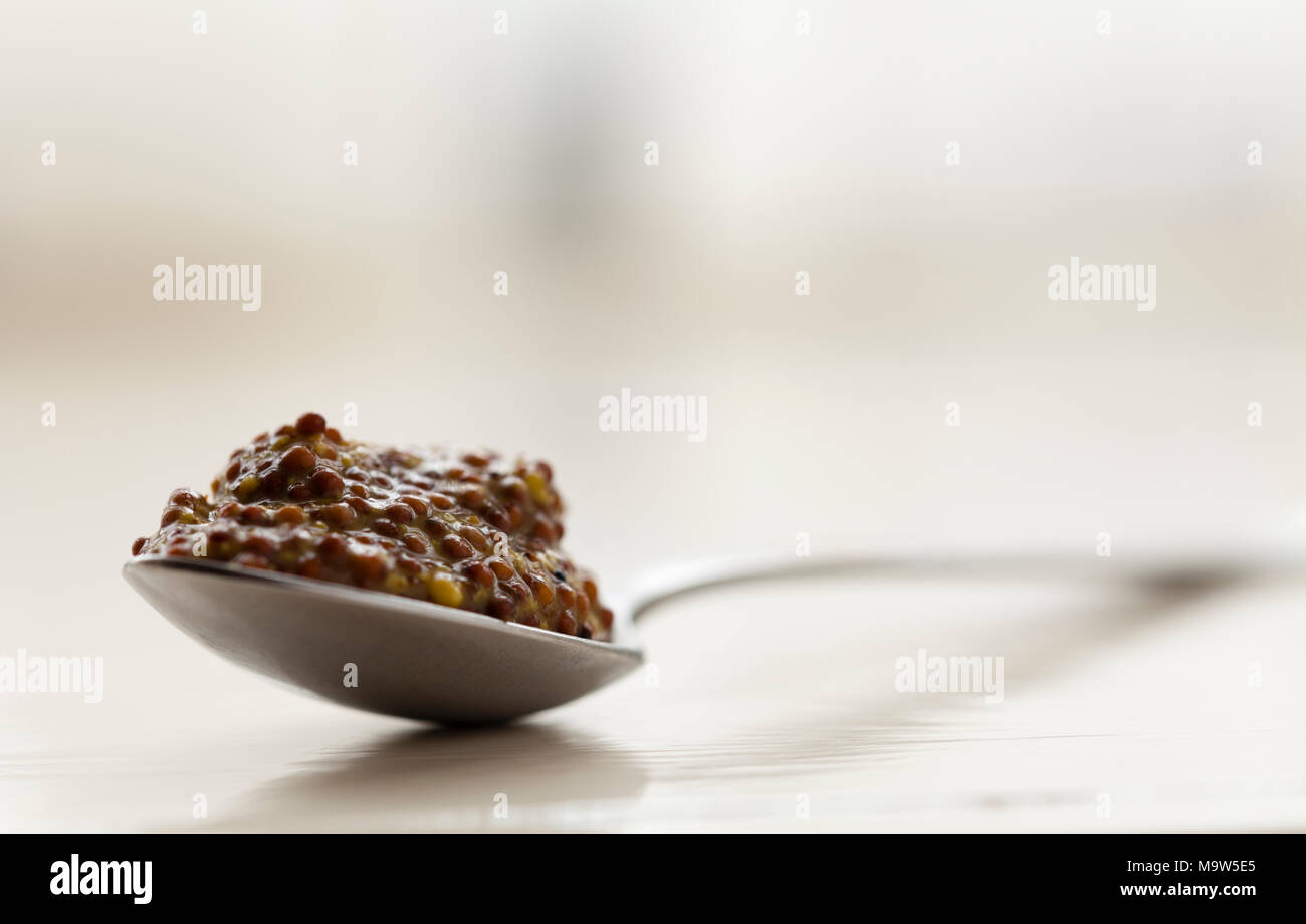 Un cucchiaino colmo di senape integrali shot in luce naturale con molto leggera profondità di campo a. Foto Stock
