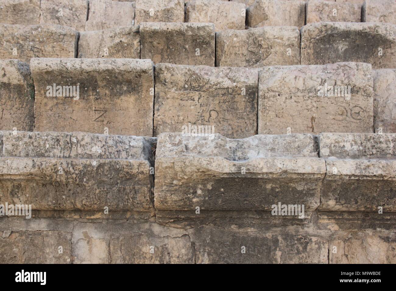 I sedili anteriori nel teatro romano di Jerash in Giordania. I Greci lettere intagliate sulla parte anteriore dei sedili riservati per l'elite della città. Foto Stock