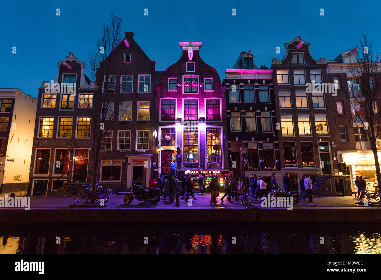 Sera ore blu vista lungo Oudezijds Achterburgwal canal street nel famoso quartiere a luci rosse di Amsterdam, Paesi Bassi. Foto Stock