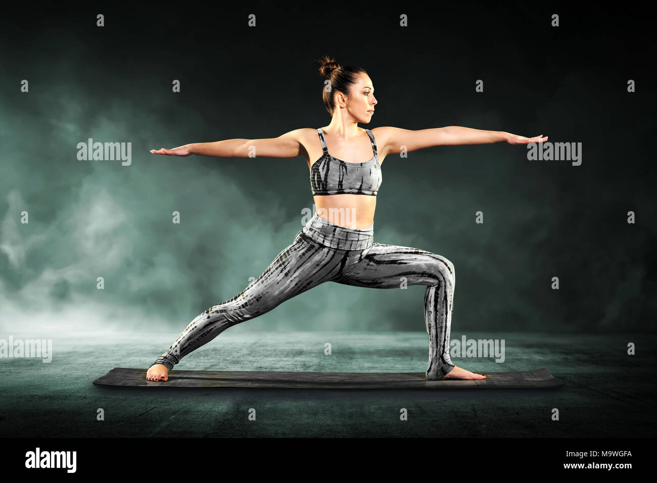 Montare athletic giovane donna dimostrando il guerriero 2 pone in yoga stretching affondo in avanti dritto con le braccia tese Foto Stock