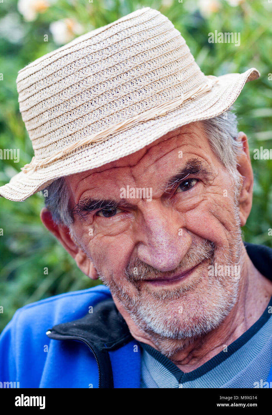 Un ritratto di un bel, sorridente uomo anziano in hat in piedi al di fuori. Foto Stock