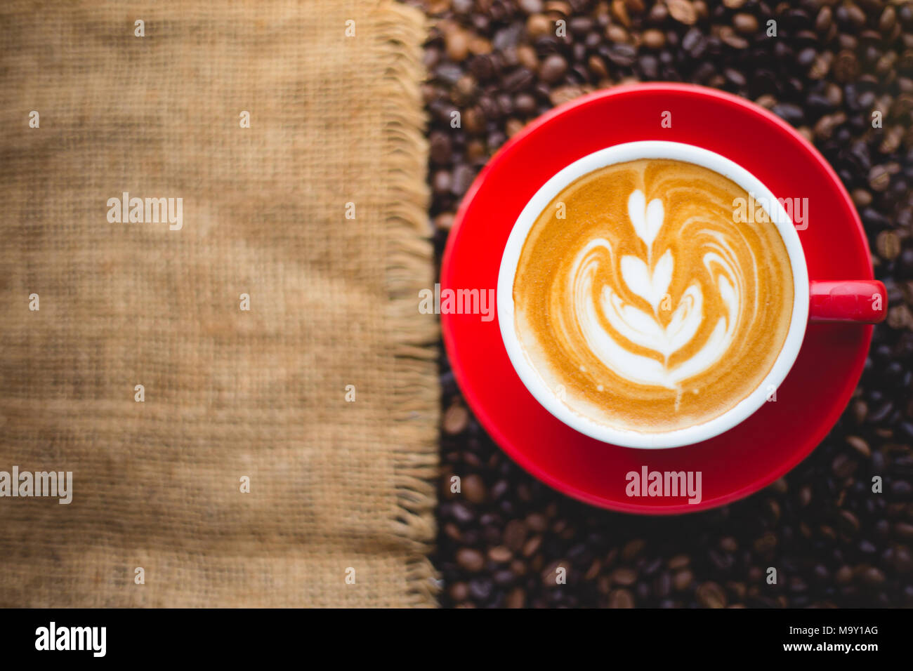Una tazza di latte art sul chicco di caffè sfondo con sacco Foto Stock