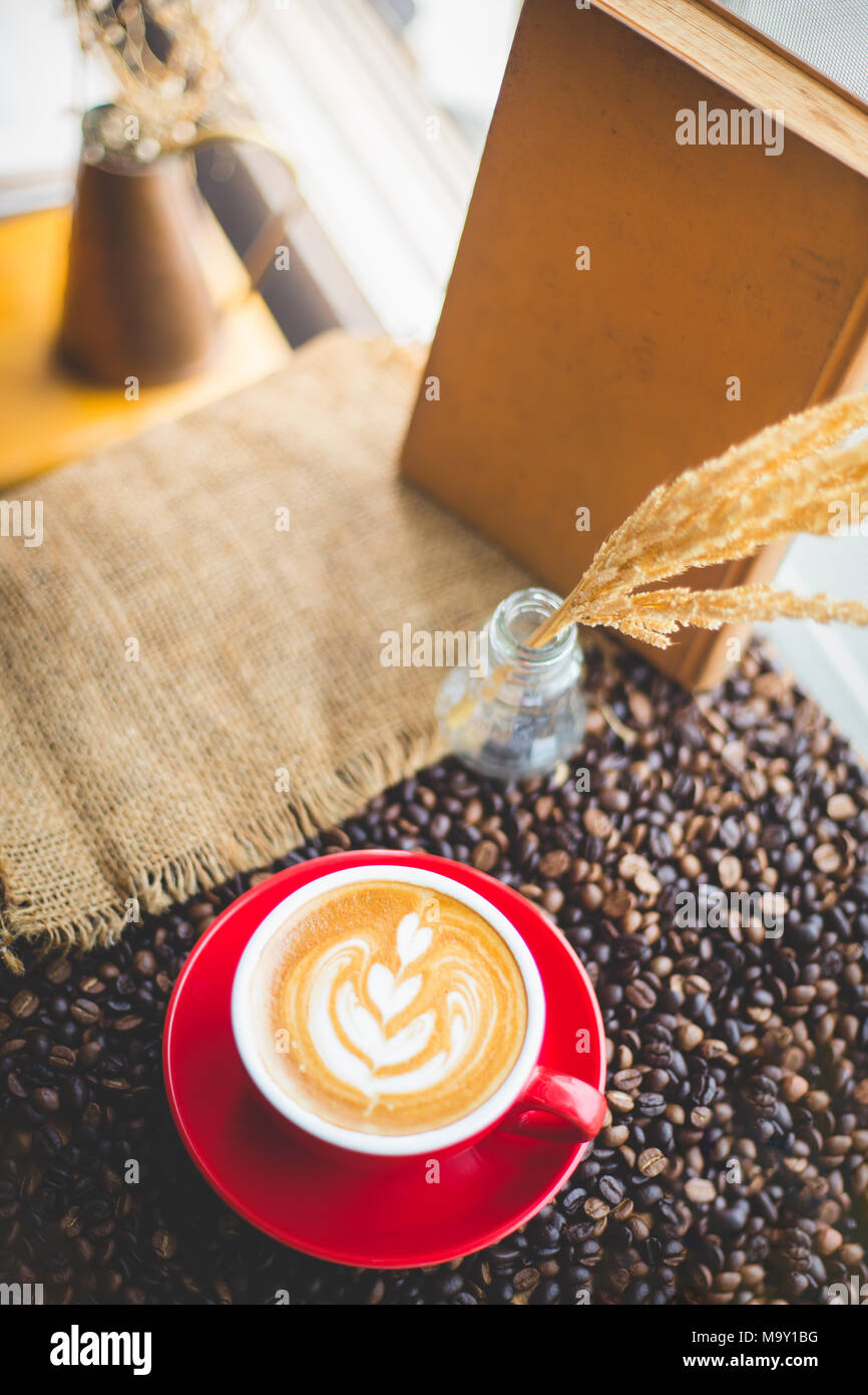 Una tazza di latte art sul chicco di caffè sfondo con sacco Foto Stock