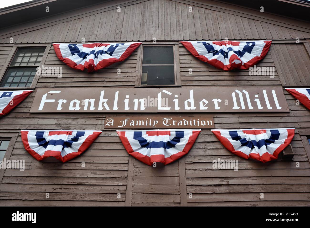 Segno sul lato della costruzione in legno "una tradizione di famiglia' con patriottici bunting flags, storico 1837 Franklin Cider Mill, Bloomfield Hills, Michigan, Stati Uniti d'America. Foto Stock