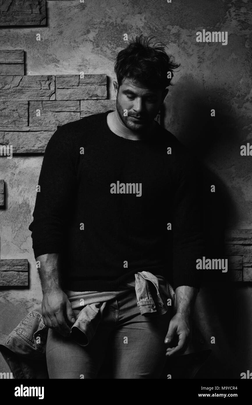 Ritratto di bello uomo barbuto vestito in abiti alla moda in piedi contro la parete dello sfondo con area per il contenuto pubblicitario - Hipster Guy Posin Foto Stock