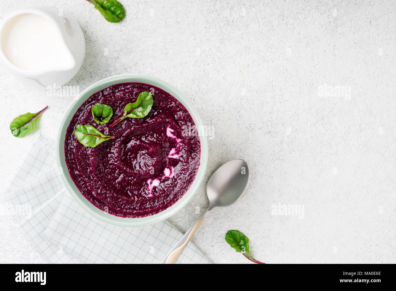 Barbabietole minestra di crema nella ciotola sulla pietra bianca dello sfondo. Detox purea di barbabietole con foglie di bietole. Dieta, pulire mangiare, dimagrimento, cibo vegetariano concep Foto Stock