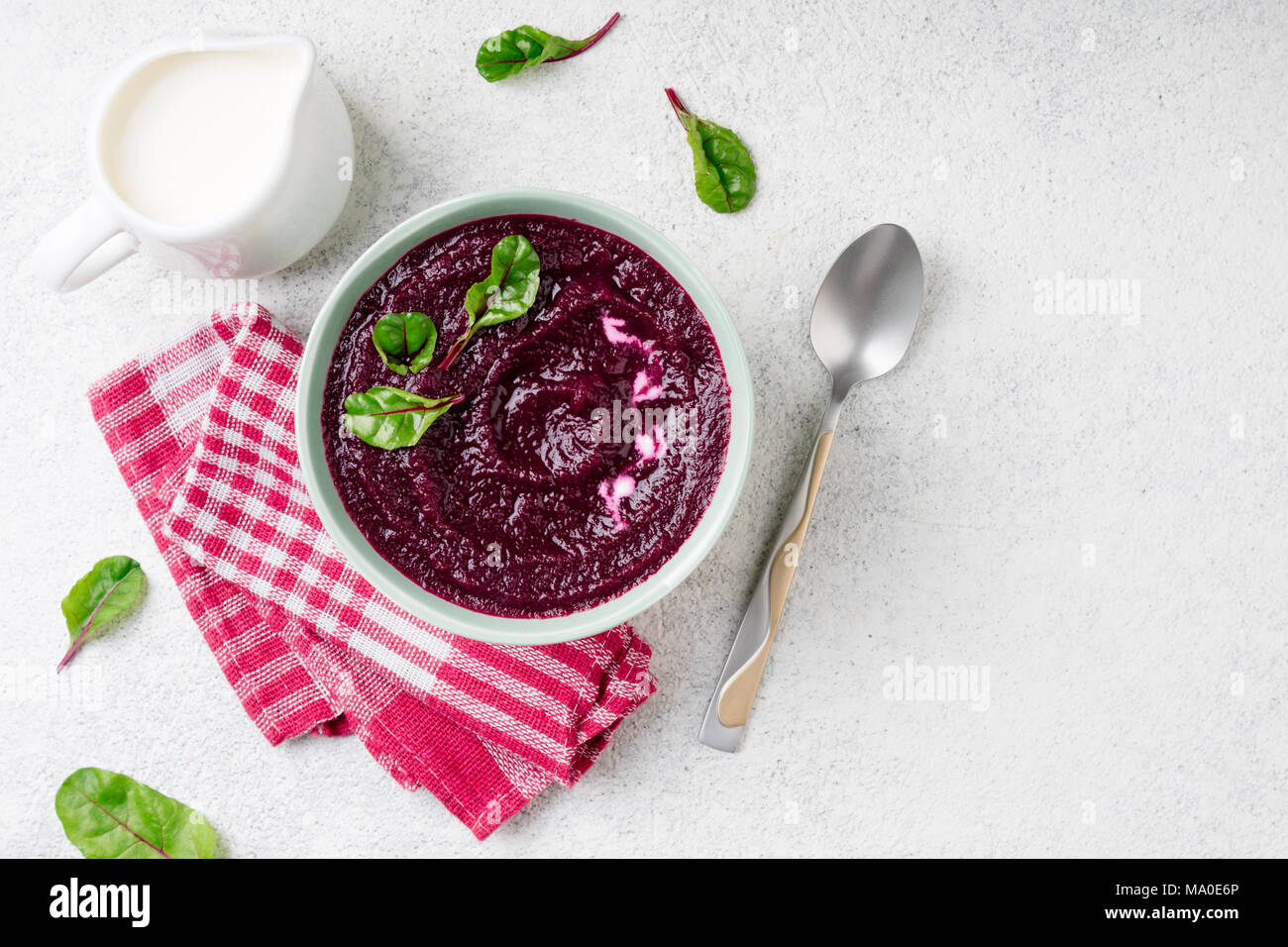 Barbabietole minestra di crema nella ciotola sulla pietra bianca dello sfondo. Detox purea di barbabietole con foglie di bietole. La dieta, pulire mangiare, dimagrimento, cibo vegetariano concetto. Foto Stock