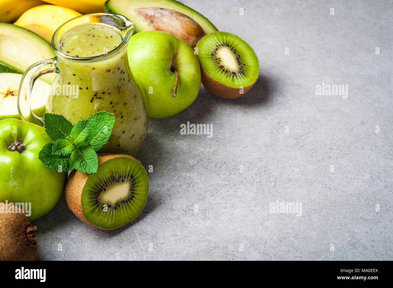 Un sano frullato verde in bottiglia e ingredienti. Cibo sano, superfoods, disintossicazione, dieta. Kiwi, Apple, spinaci, avocado, banana e menta. Vegetariano fo Foto Stock