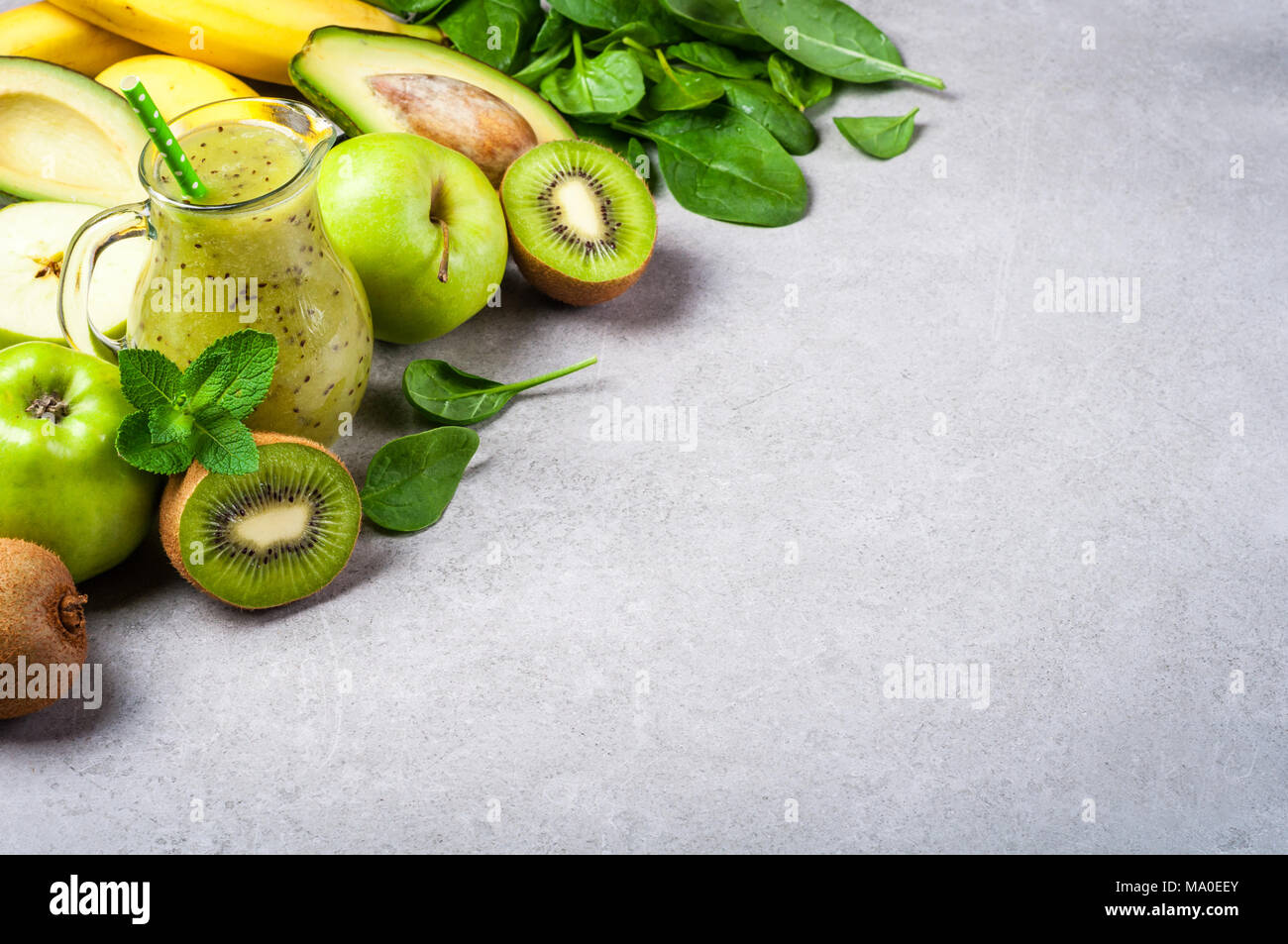 Un sano frullato verde in bottiglia e ingredienti. Cibo sano, superfoods, disintossicazione, dieta. Kiwi, Apple, spinaci, avocado, banana e menta. Vegetariano fo Foto Stock