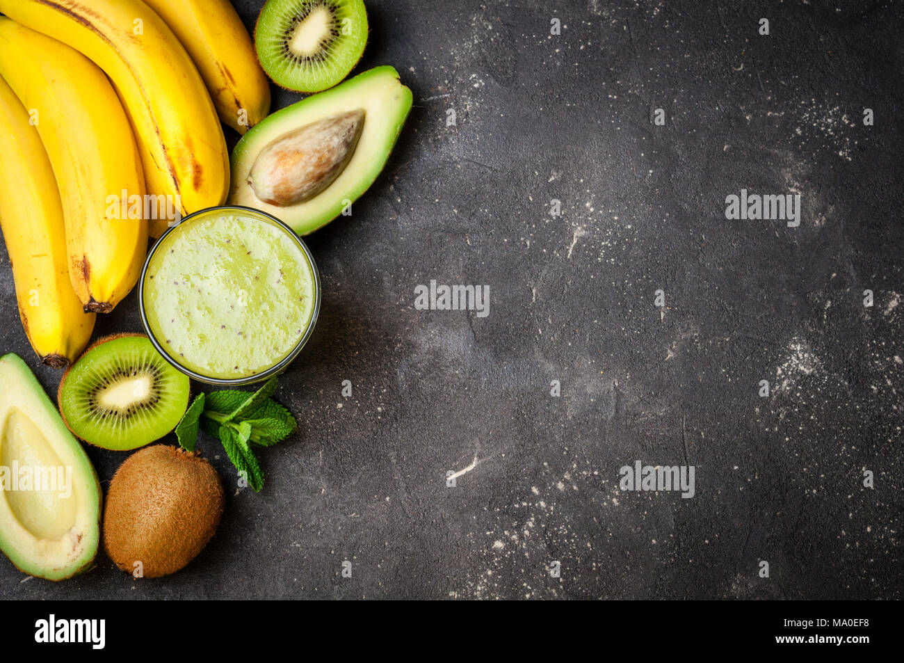Un sano frullato verde e gli ingredienti su sfondo scuro. Frullato di kiwi con frutti. Concetto superfoods, dieta disintossicante, salute cibo vegetariano Foto Stock