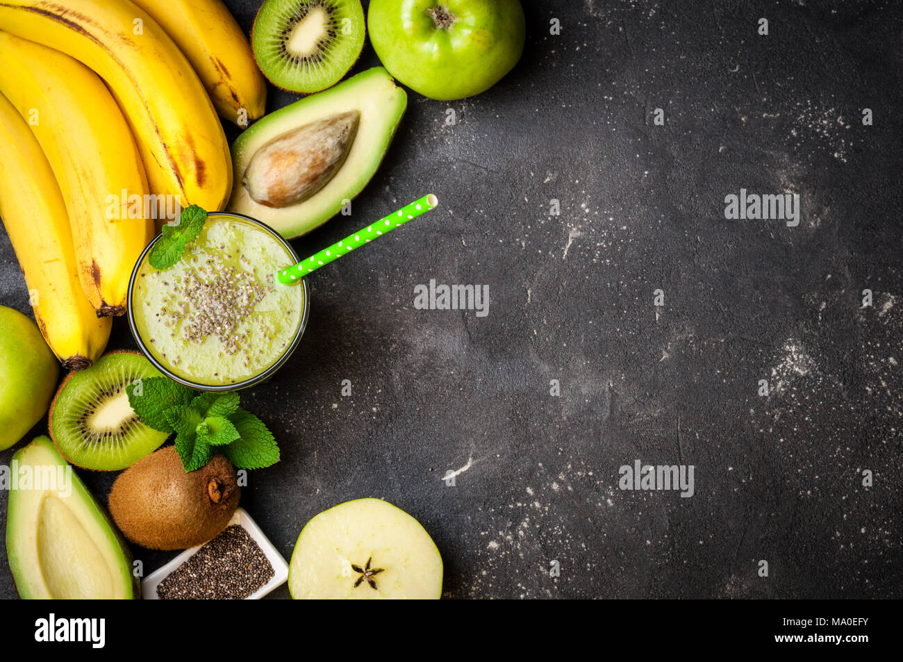 Un sano frullato verde e gli ingredienti su sfondo scuro. Frullato di kiwi con frutti. Concetto superfoods, dieta disintossicante, salute cibo vegetariano Foto Stock