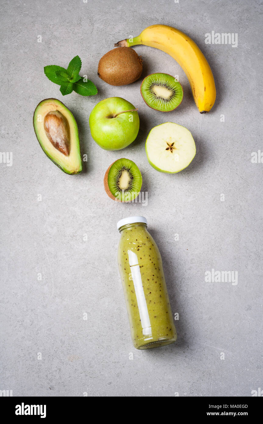 Un sano frullato verde in bottiglia e ingredienti. Cibo sano, superfoods, disintossicazione, dieta. Kiwi, Apple, spinaci, avocado, banana e menta. Vegetariano fo Foto Stock