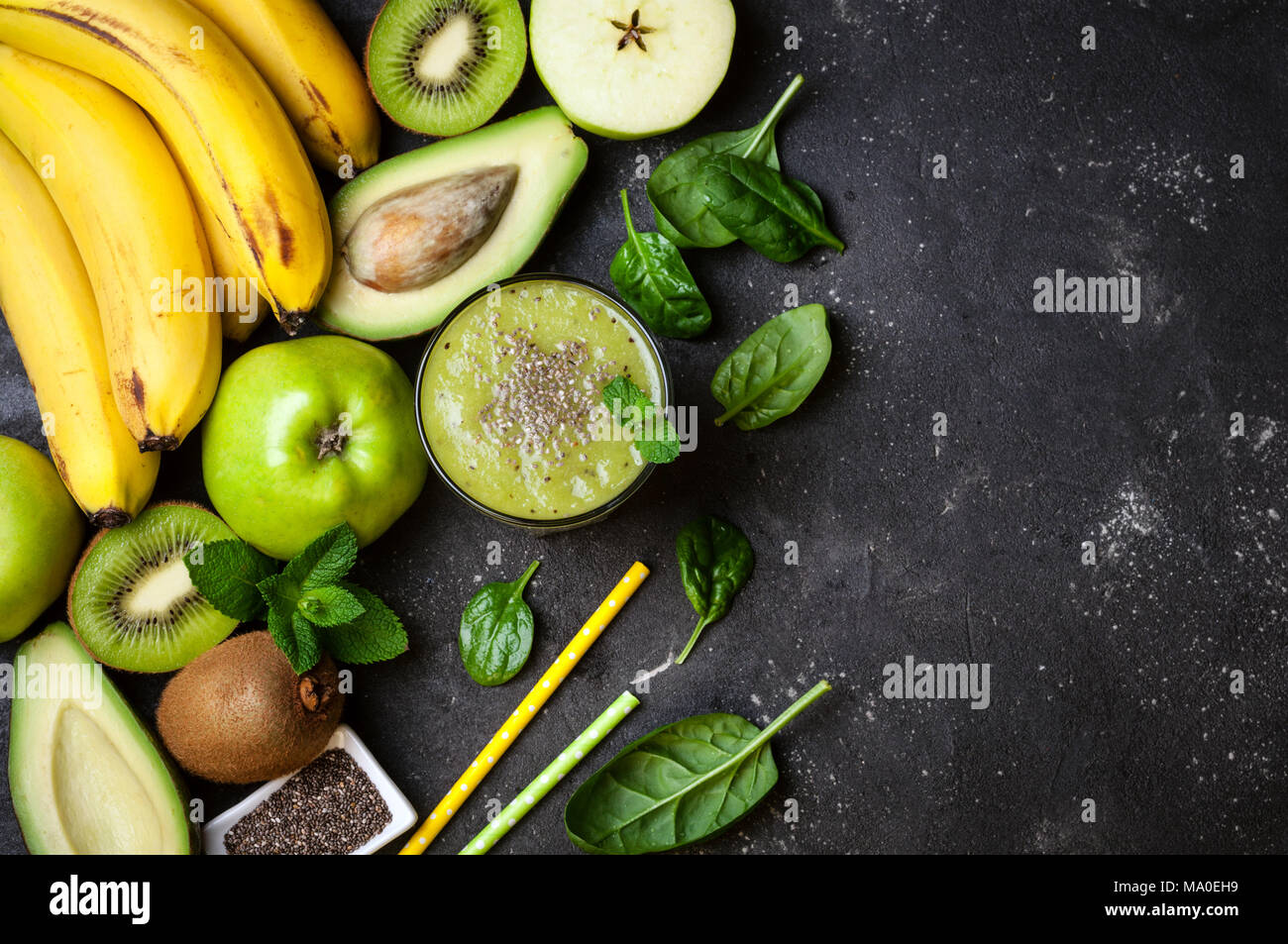 Un sano frullato verde e gli ingredienti su sfondo scuro. Frullato di kiwi con frutti e semi di Chia. Superfoods, dieta disintossicante, salute cibo vegetariano Foto Stock