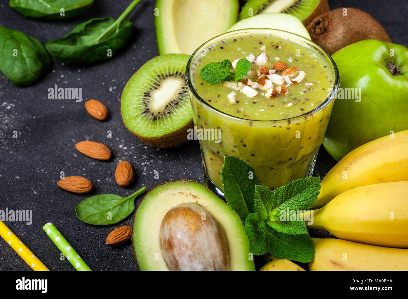 Frullato sano e gli ingredienti su sfondo scuro. Frullato di kiwi con frutti. Concetto superfoods, dieta disintossicante, salute cibo vegetariano. Vista superiore Foto Stock