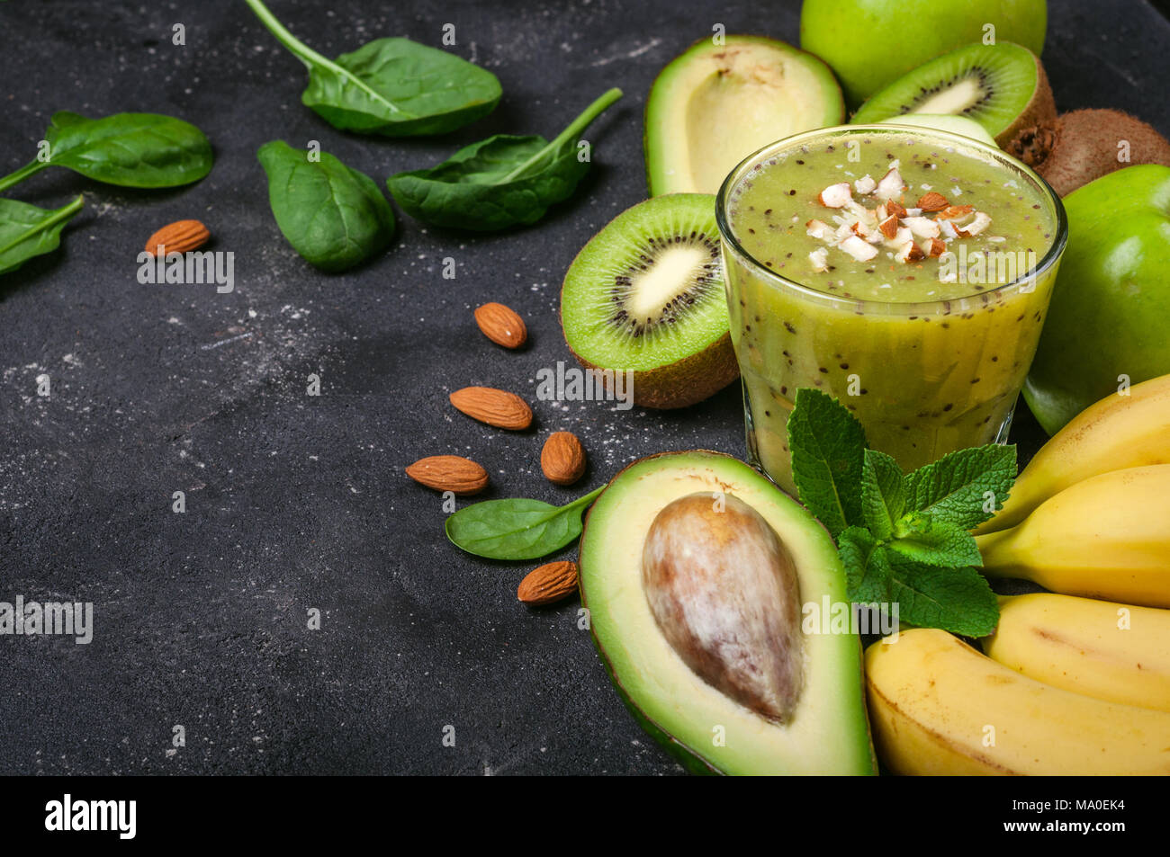 Un sano frullato verde e gli ingredienti su sfondo scuro. Frullato di kiwi con frutti. Superfoods, dieta disintossicante, salute cibo vegetariano concept Foto Stock
